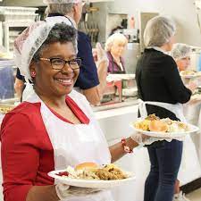 A woman holding two plates of food in her hands.