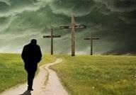 A person walking down the road towards three crosses.