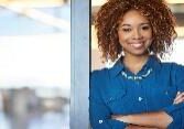 A woman with curly hair standing in front of a window.